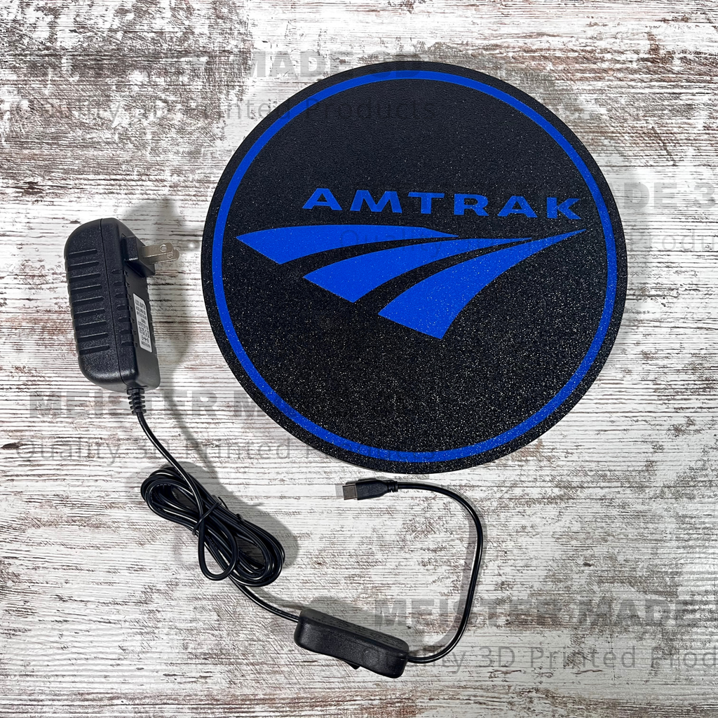 Amtrak LED light up sign with a black powersupply beside it that has a on/off switch and usb-c connector all on a wood background