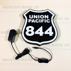 Union Pacific 844 illuminated railroad sign with included power adapter and inline switch, featuring a black and white locomotive shield design for train room decor.