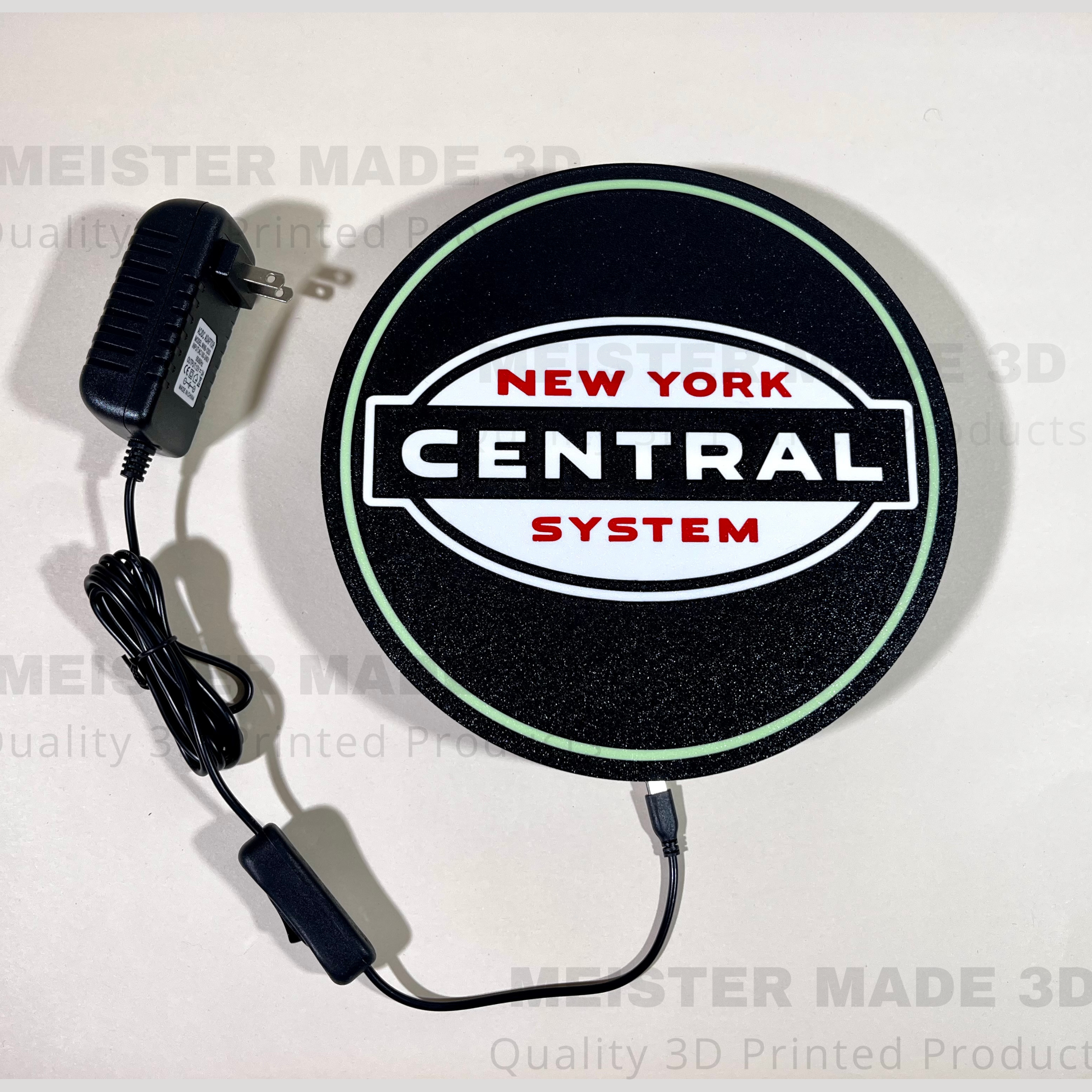 Round sign with 'New York Central System' logo and power adapter on a white background