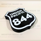 Angled close-up of a Union Pacific 844 railroad shield LED sign, featuring a black background, white lettering, and illuminated white border in a 3D printed design.