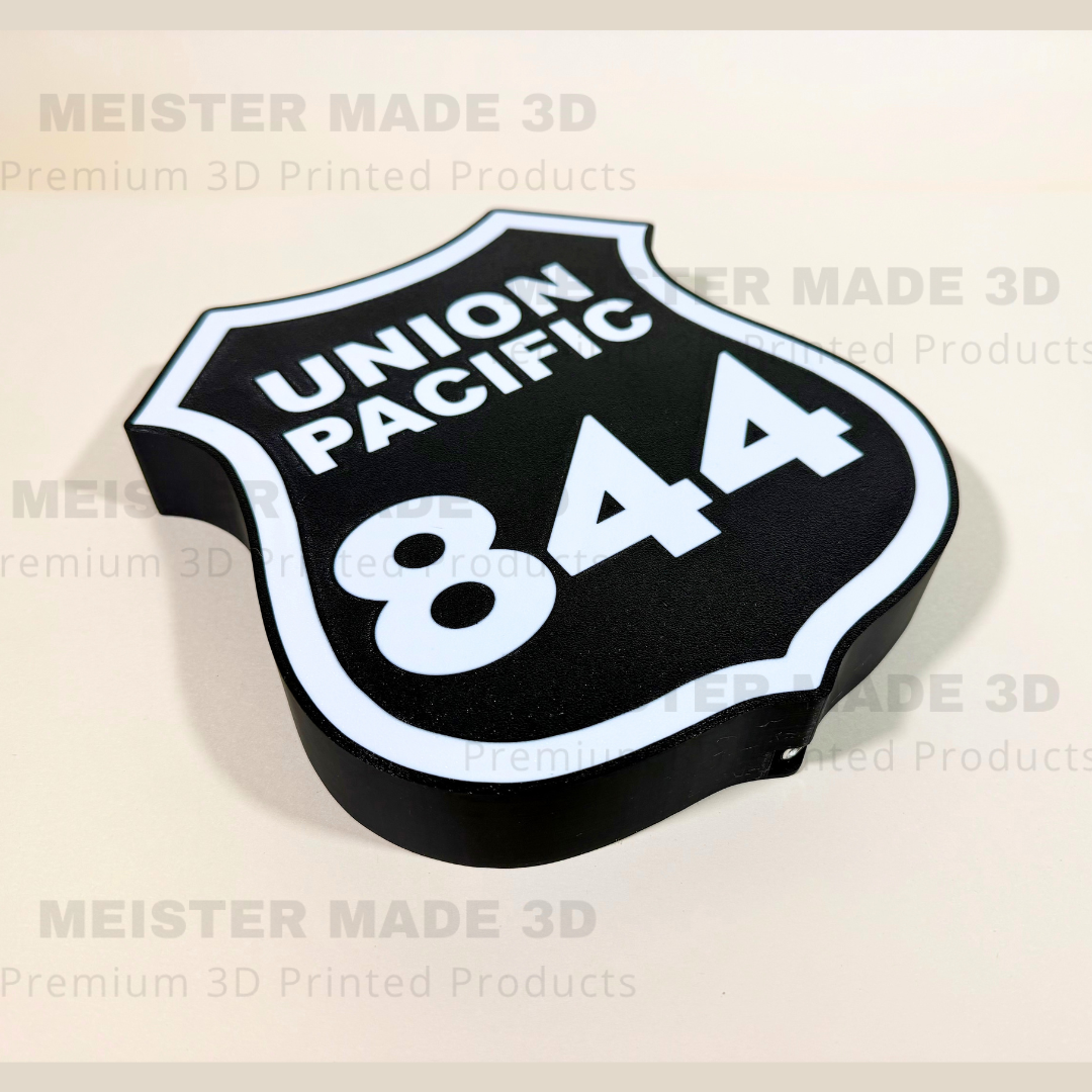 Angled close-up of a Union Pacific 844 railroad shield LED sign, featuring a black background, white lettering, and illuminated white border in a 3D printed design.