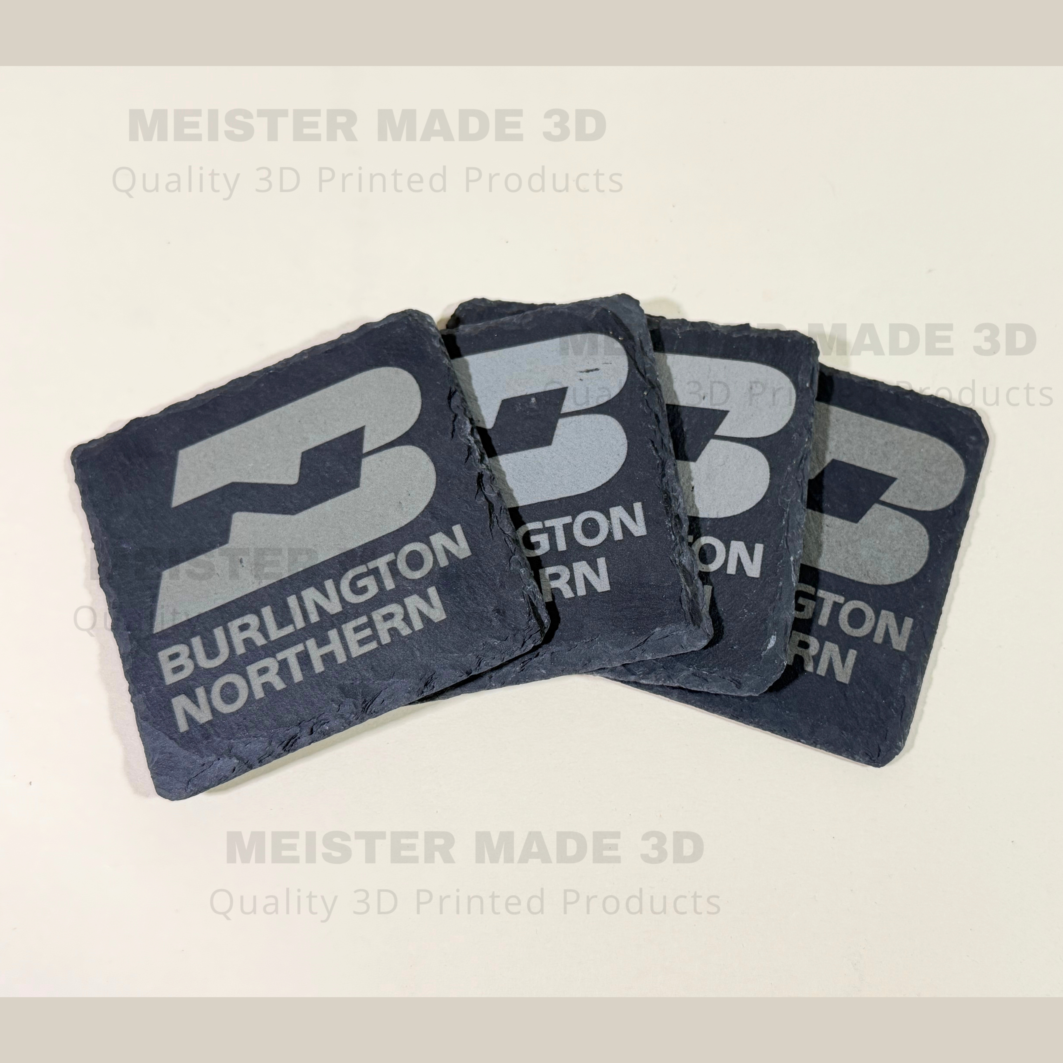 Four laser engraved Burlington Northern slate coasters displayed in a fan arrangement, showcasing natural stone edges and detailed BN railroad logo engraving.