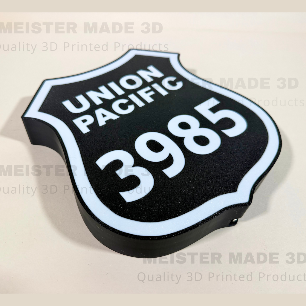A 3D printed black shield-shaped sign with white lettering reading 'UNION PACIFIC' and the number '3985', shown on a light beige background with a faint Meister Made 3D watermark.