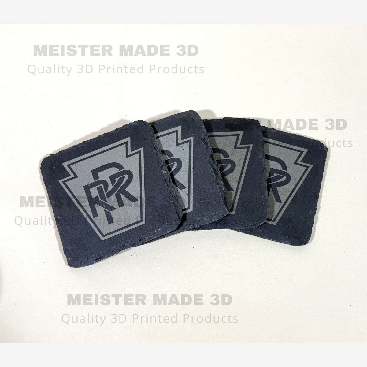 Set of four black slate coasters featuring the Pennsylvania Railroad PRR keystone logo engraved in gray, with natural rough slate edges.