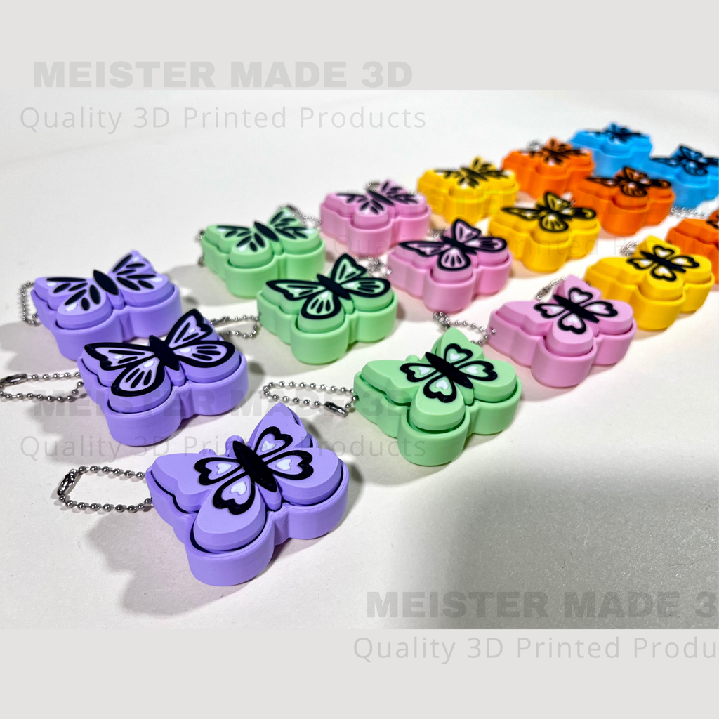 Colorful butterfly-shaped keychains with a chain on a white background, branded 'MEISTER MADE 3D'.