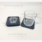 Pennsylvania Railroad PRR slate coaster shown with a drinking glass, featuring the engraved PRR keystone logo and natural black slate finish.