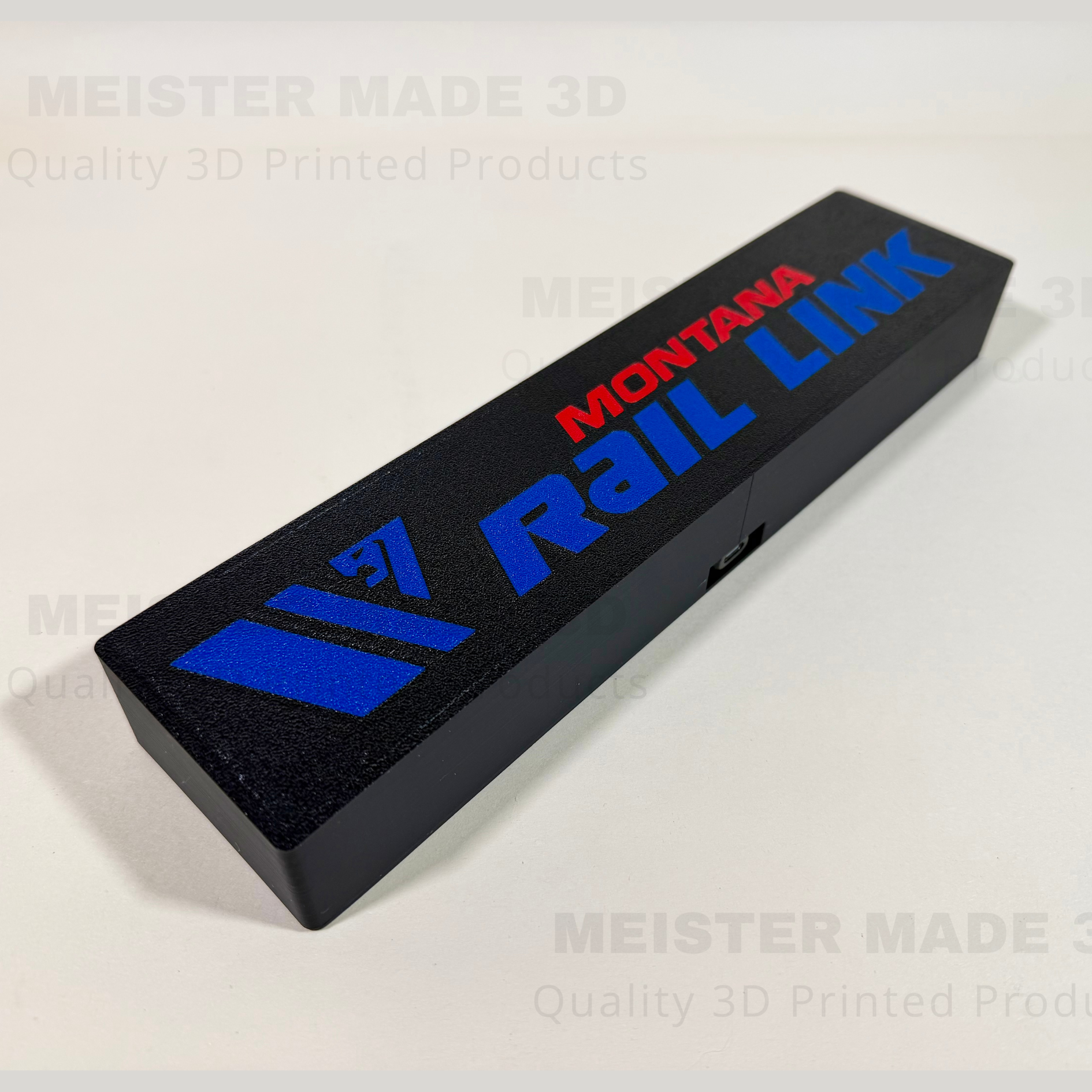 Angled view of Montana Rail Link illuminated sign showing textured black finish and raised blue and red lettering.