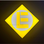 Illuminated sign. Yellow and gray logo with the letter 'E' on a dark background