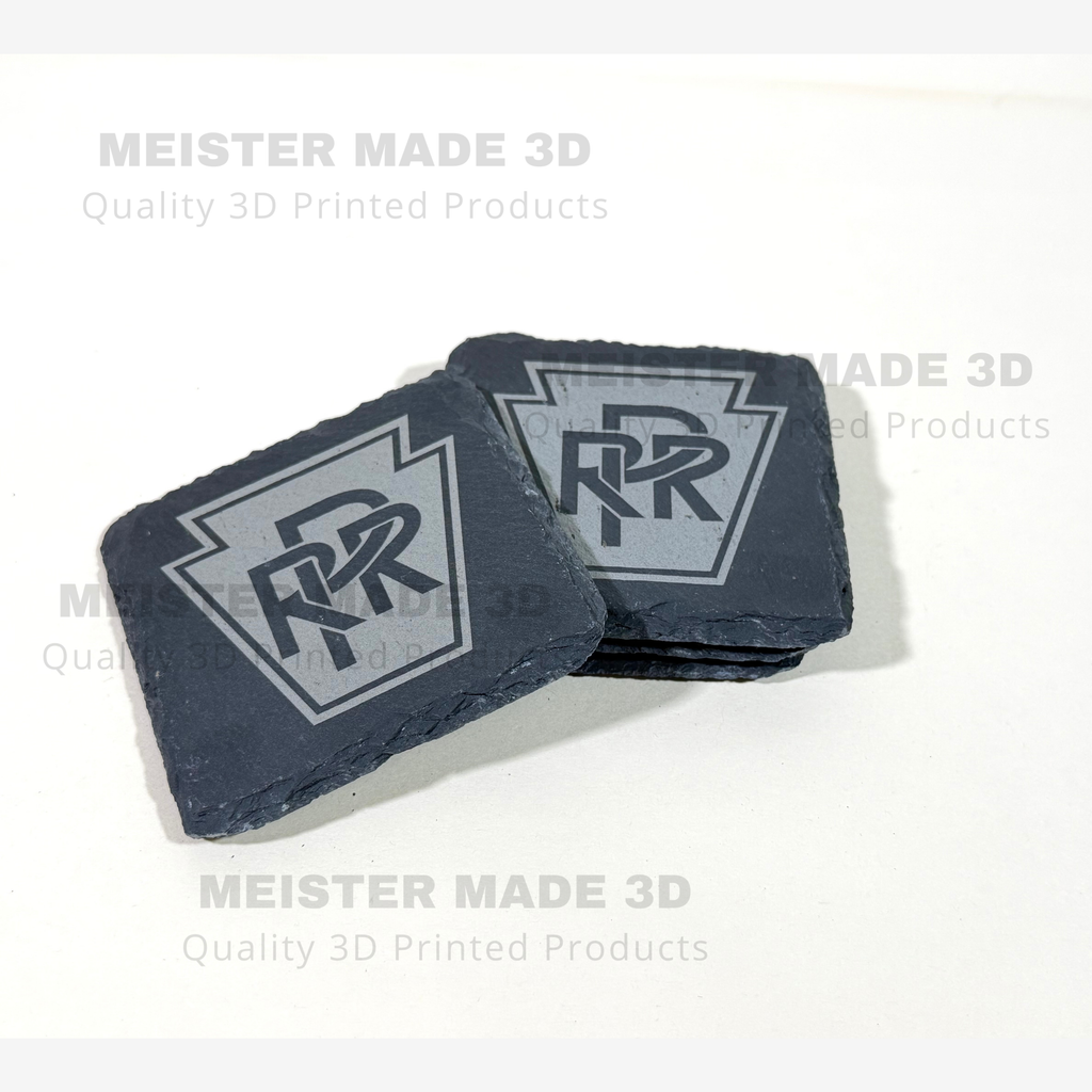 Stack of black slate Pennsylvania Railroad coasters featuring the engraved PRR keystone logo and natural textured slate edges.