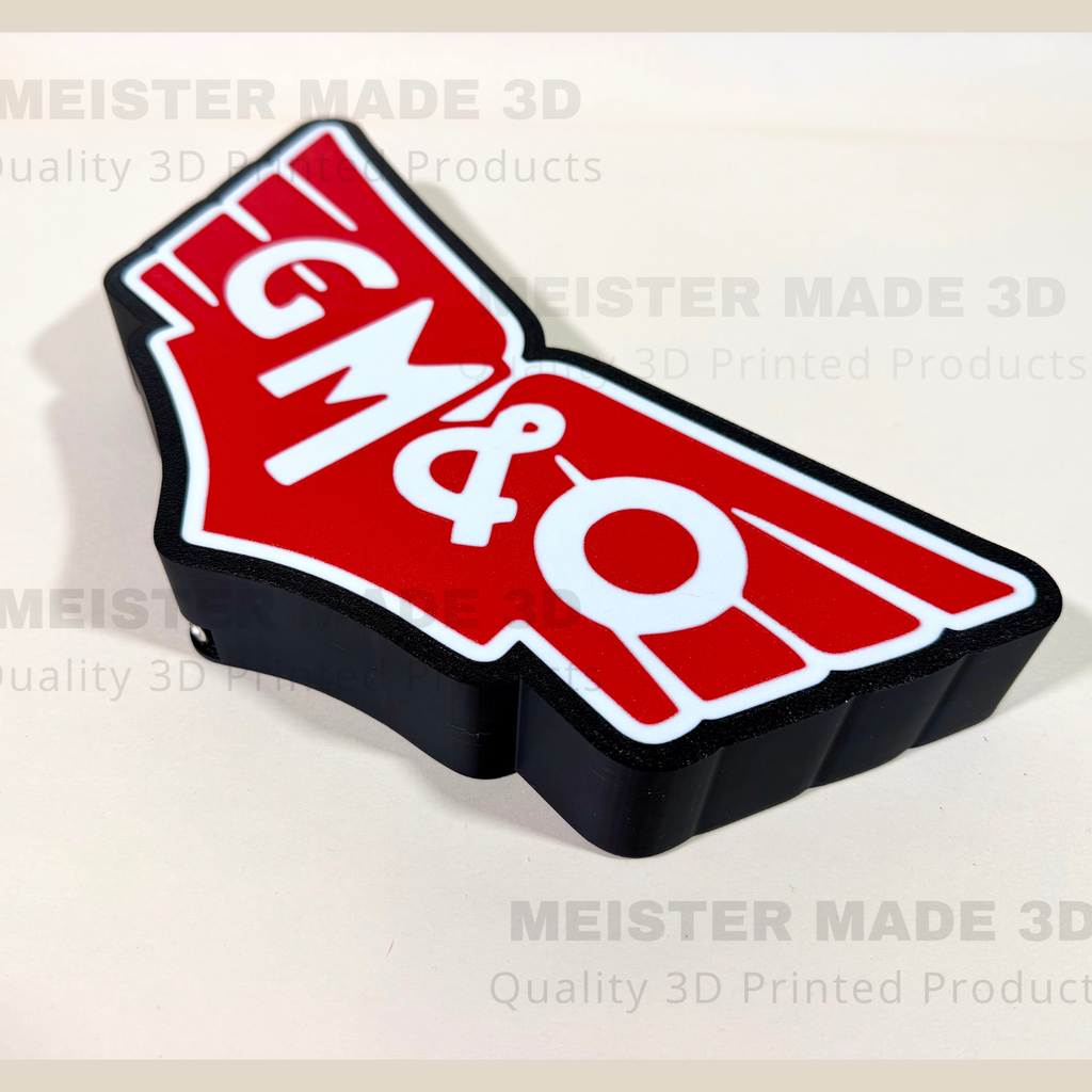 A 3D printed GM&O logo sign with a red and white top section and a black base, shown on a light beige background with 'MEISTER MADE 3D' watermarks.
