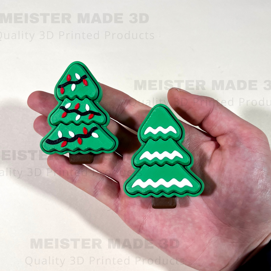 Hand holding 2 3d printed christmas tree fidget clicker toys to give an idea of size
