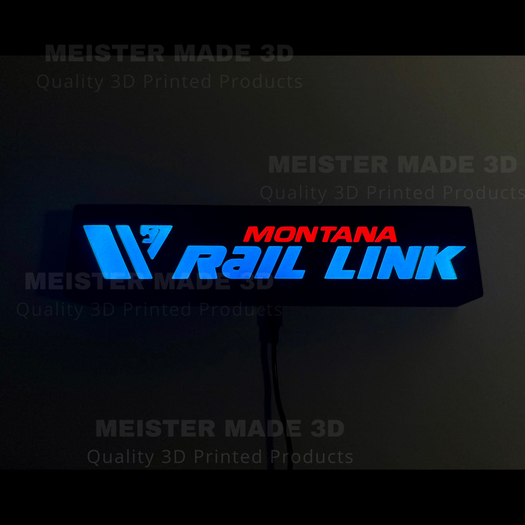 Montana Rail Link LED sign illuminated in dark setting with glowing blue and red lettering for railroad room or office decor.