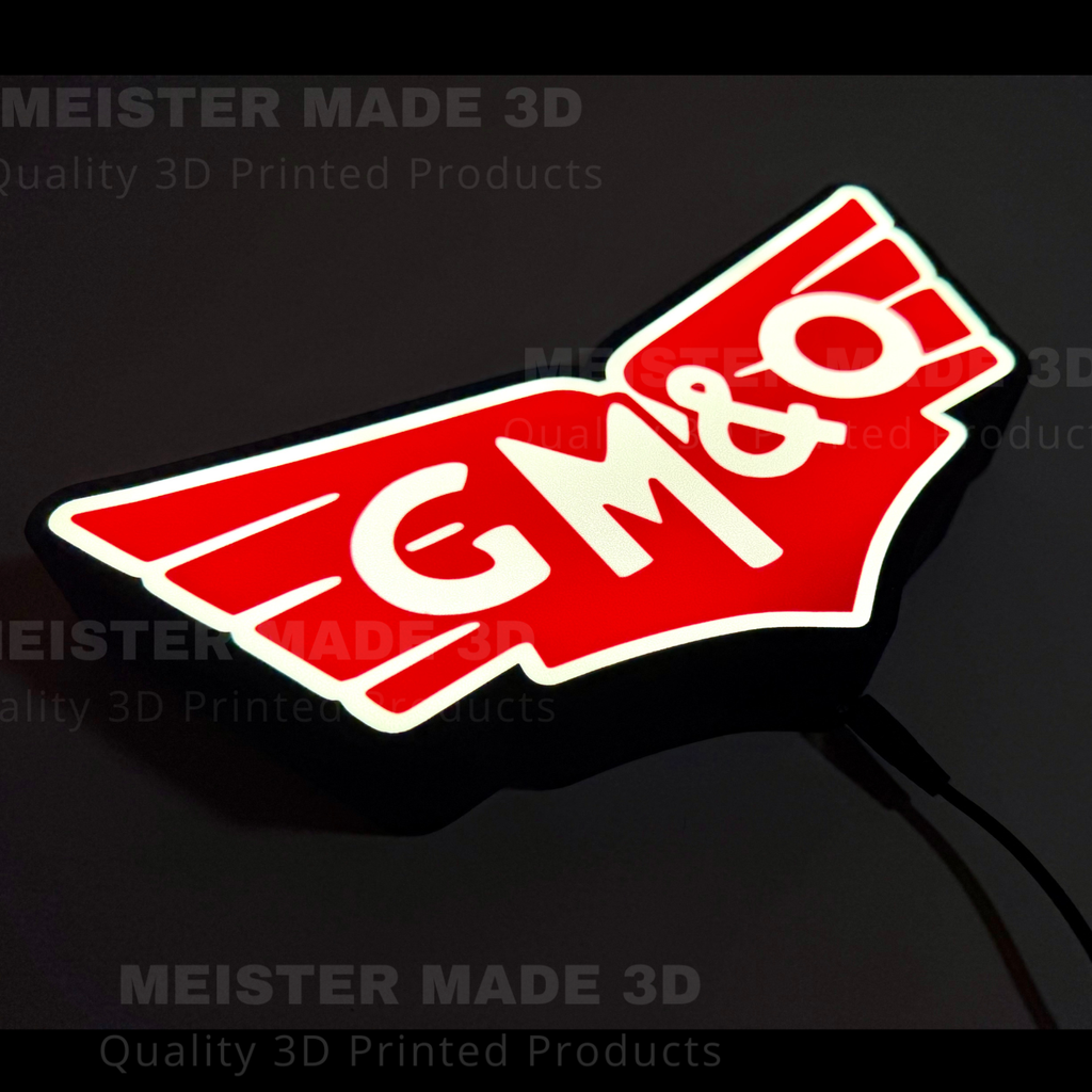 A 3D printed illuminated sign featuring the red and white GM&O logo, shown against a dark background with a power cord visible.